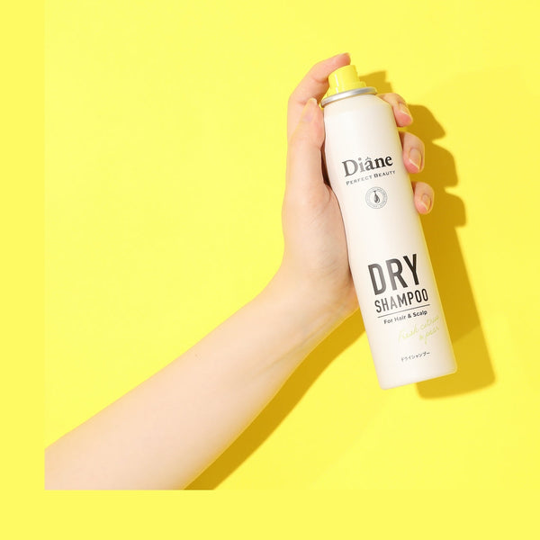 holding Perfect Beauty Dry Shampoo Fresh Citrus & Pea on yellow background
